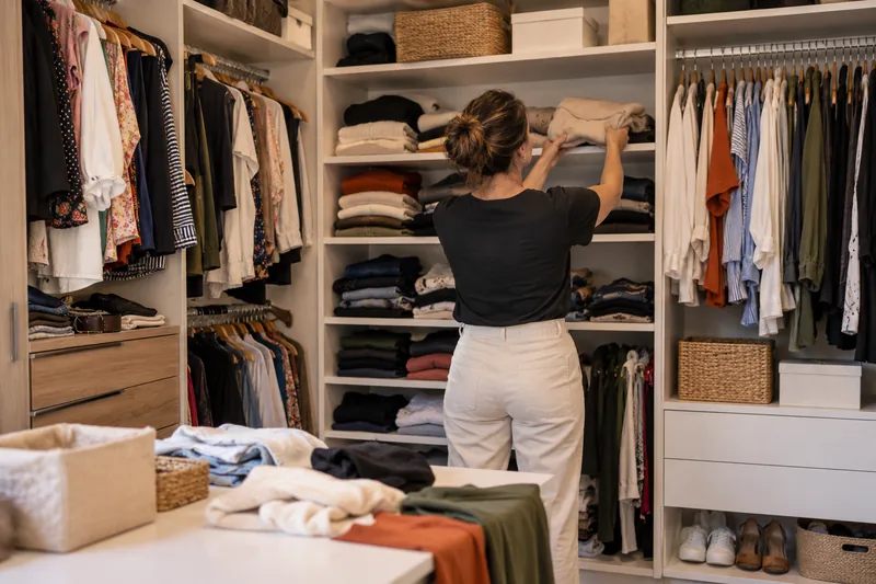 Personal organizer de costas organiza roupas em um closet residencial.
